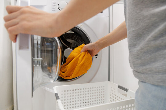 Taking clean laundry out of a washing machine after a wash cycle. Everyday household chore, laundry routine, clean clothes, home cleaning and domestic work.