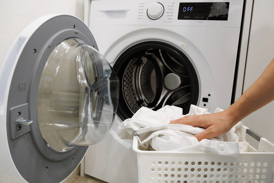 Laundry basket full of washed clothes beside a washing machine. Simple home cleaning routine with fresh clothes ready for drying after laundry.