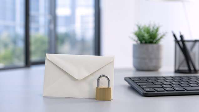 White envelope with brass padlock on office desk. Secure communication and email data privacy concept