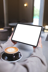Vertical mockup image of a woman holding digital tablet with blank white desktop screen in cafe © Farknot Architect