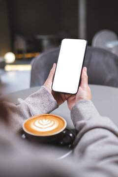 Vertical mockup image of a woman holding mobile phone with blank desktop screen in cafe
