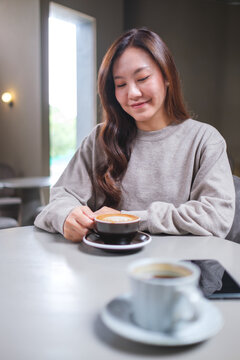 Portrait image of a woman holding and drinking coffee with friend in cafe