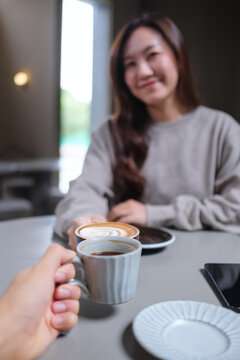 Vertical image of couple people clinking coffee cups in cafe