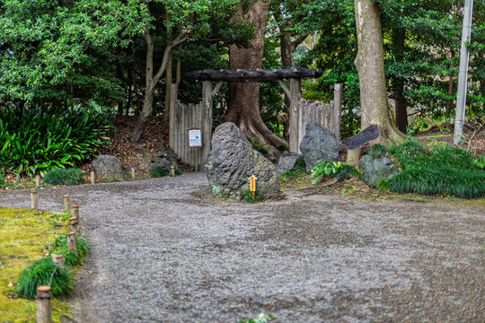 Famous Iyo-aoishi stone on a gravel path leading to a rustic wooden gate at Kiyosumi Gardens March 2024