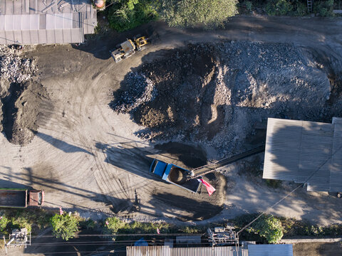 Aerial view of a stone crushing operation with heavy machinery, trucks, and piles of gravel at an industrial site in Kecamatan Karangnongko, Jawa Tengah, Indonesia.