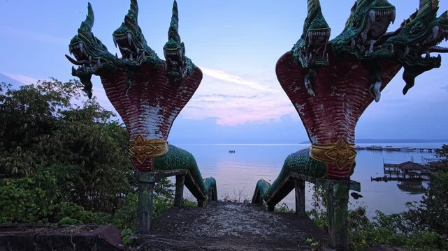 Ancient buddhist temple in Thailand with twin naga statues, dusk and pagoda
