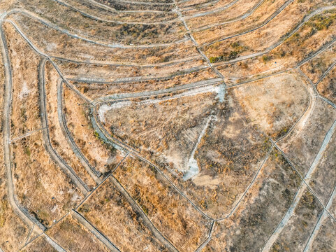 Aerial view of the arid terraced landscape at Puncak Sosok with dry fields and winding paths in Kecamatan Pleret, Daerah Istimewa Yogya, Indonesia.