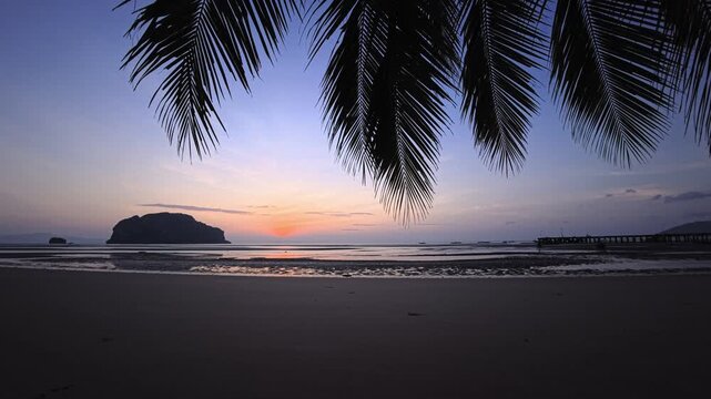 Sunrise on a paradisiacal sandy beach on a tropical island in Thailand with low tide and palm trees