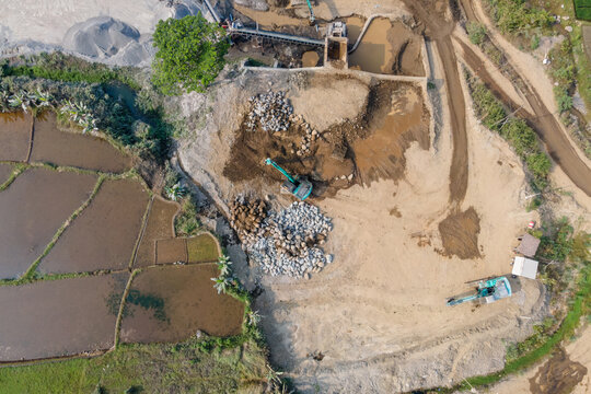 Mining Work on a Large-Scale Rock and Sand Quarry Industrial Site, Excavator Operating Near a Stone Crusher. Active Mining and Aggregate Processing Facility Captured from Above.