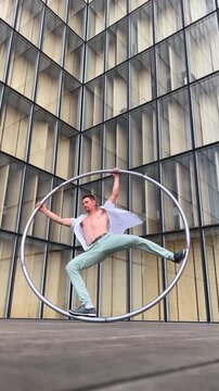 Dynamic and vibrant performance of a Cyr Wheel within urban architecture, vertical video. Concept of originality, creativity and outstanding