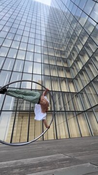 Dynamic and vibrant performance of a Cyr Wheel within urban architecture, vertical video. Concept of individuality, creativity and self-confidence