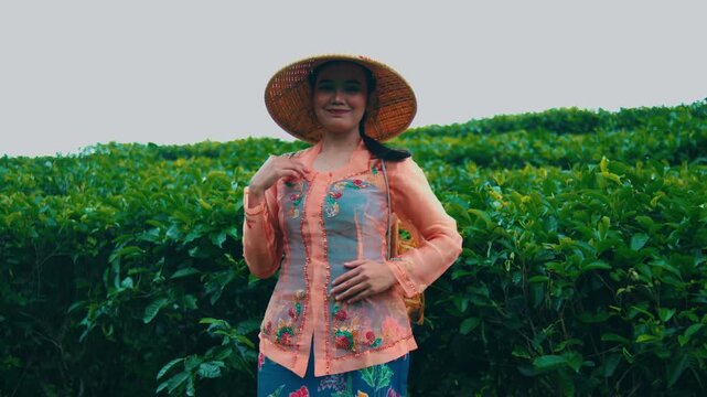 Portrait of Smiling Indonesian Woman in Traditional Kebaya and Farmer Hat at Tea Plantation