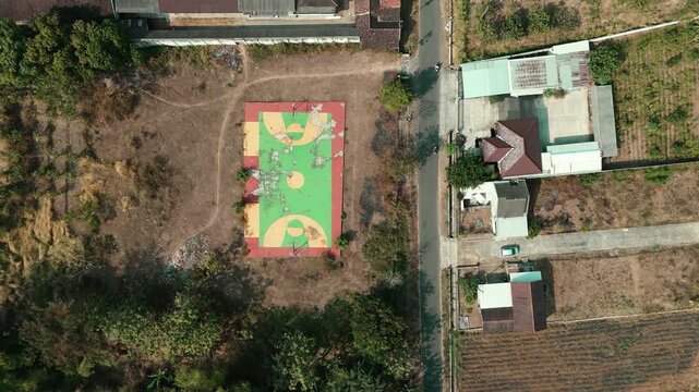 Aerial drone view of agricultural farmlands featuring harvested sugarcane fields, newly plowed soil, pomelo orchards, and a rural village during daytime.