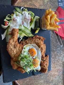 Wiener Schnitzel vom Kalb mit Spiegelei, frischem Salat und knusprigen Pommes frites. Klassisches Restaurantgericht, &ouml;sterreichische K&uuml;che, Hausmannskost und authentische Food-Fotografie.