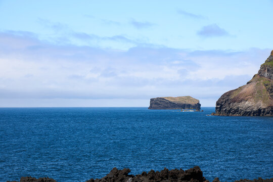 Volcanic rock islets and rugged coastal cliffs in deep blue ocean water