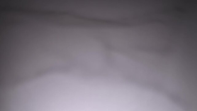 Defocused blurred transparent plastic film creates soft gray reflections and abstract bokeh. Concept background for packaging, advertising, banners, websites and digital design.