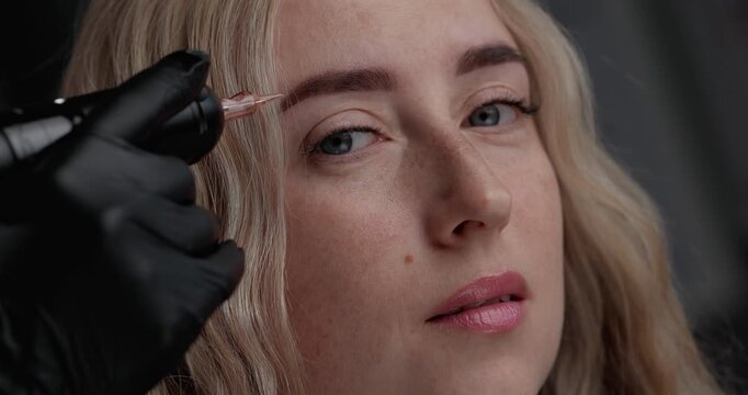 Closeup tracking handheld shot of woman receiving eyebrow tinting treatment in beauty studio with applicator motion.