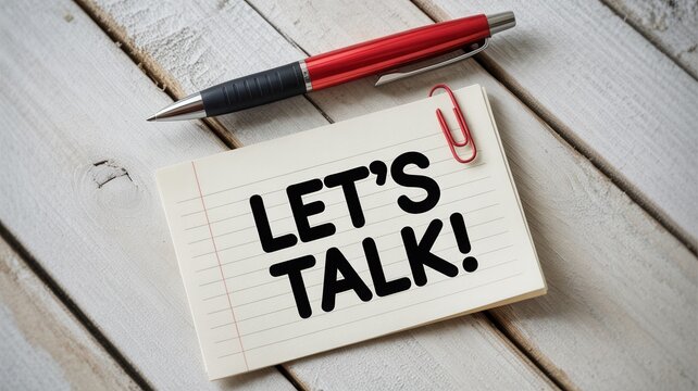 Lets talk message written on a paper notepad with a red pen and metal clip resting on wooden white boards