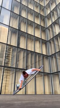 Dynamic and vibrant performance of a Cyr Wheel within urban architecture, vertical video. Concept of individuality, creativity and self-confidence