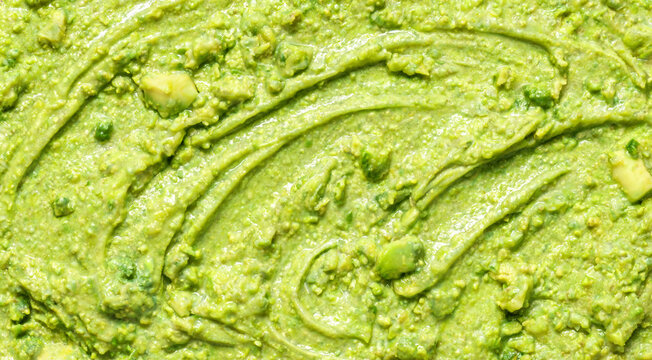 Guacamole preparation with mashed avocados and green ingredients in a bowl