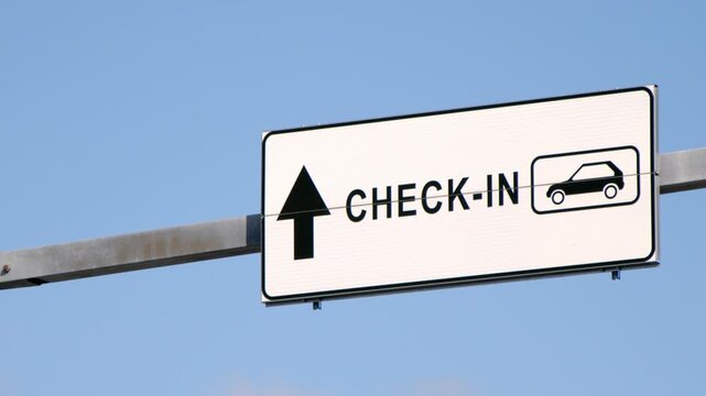 Road sign indicating vehicle check-in area with directional arrow against blue sky. Transportation and passenger terminal wayfinding concept with copy space.