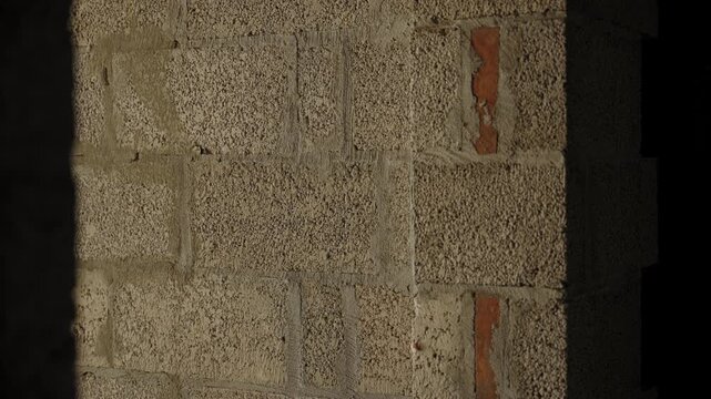 Camera movement past rough masonry wall in unfinished building