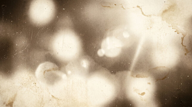Heavily distressed vintage film texture with bright light leaks and sepia bokeh effects for historical aesthetic and aged photographic design featuring cracks and chemical stains.