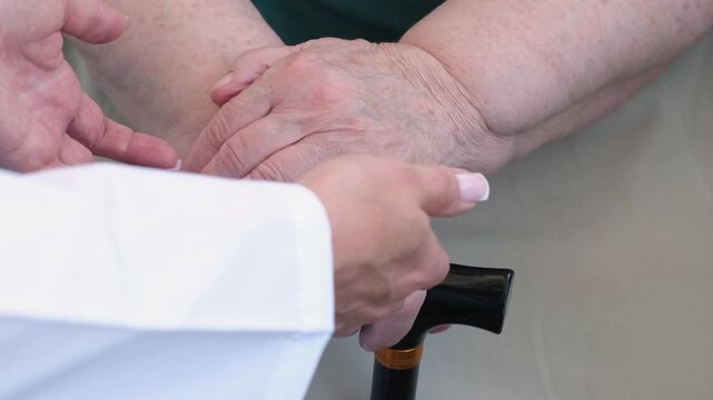 Doctor supporting senior woman, closeup. Nursing support for elderly. Caregiver take hands of old female patient. Health care in hospital