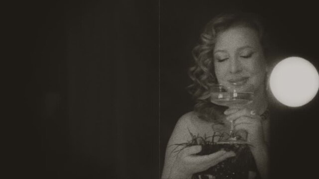 Black and white film color old style happy woman retro lady hand holding glass of white wine congratulates herself, making cheers while looking at mirror reflection conceptself love. Lips smiling face