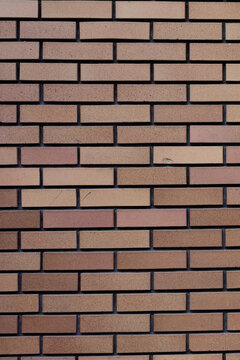 Clean and modern texture of a brown brick wall with dark mortar forming a neat geometric pattern