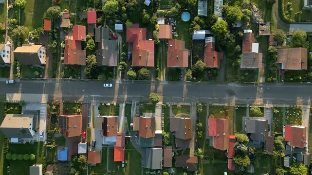 Aerial top view of suburban houses with garden pools and green lawns at summer sunset.