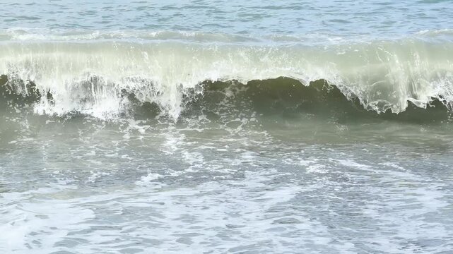 Blue sea and large waves and foam. Wave splashing over pebbles at sea. Rolling ocean waves. Summer beach background. Powerful sea waves	