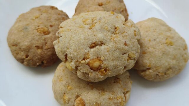 Bunch or heap of delicious round homemade butter cookie biscuits with sweet conflex chips stacked together. Traditional Asian dessert or snack food. Closeup spinning or rotation top view.