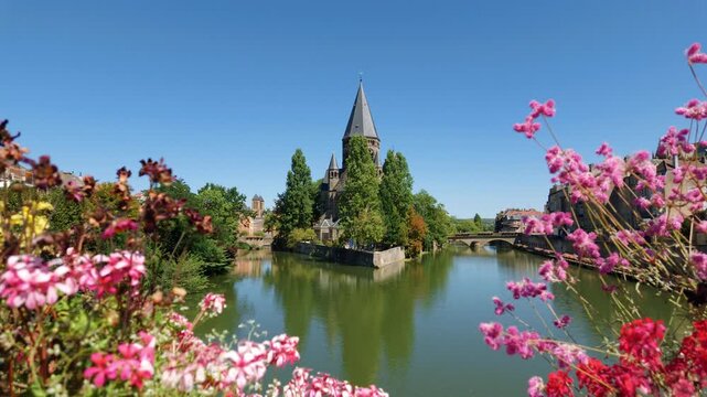 Temple Neuf on an island in the Moselle River in Metz, France, framed by pink flowers