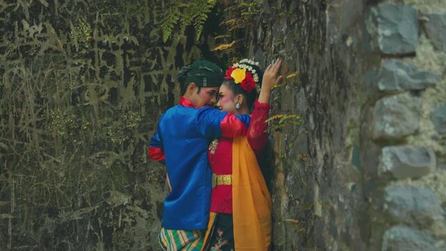 Intimate Traditional Couple Embracing Against Mossy Stone Wall