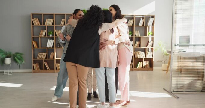 Coworkers team hug in office showing unity. Colleagues share a supportive huddle celebrating teamwork and trust. Warm body language shows encouragement and care. Symbol of unity and success.