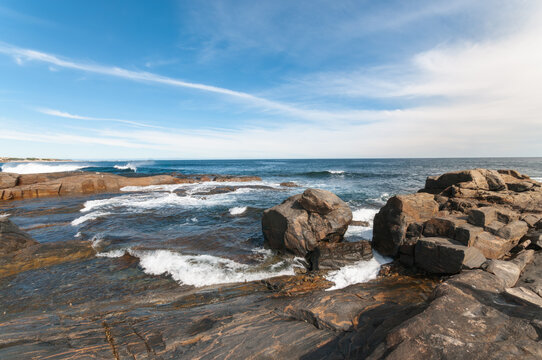 Rugged coastline at Gracetown, Western Australia, with breaking Indian Ocean waves, weathered rock formations and coastal houses overlooking the bay in the Margaret River region.