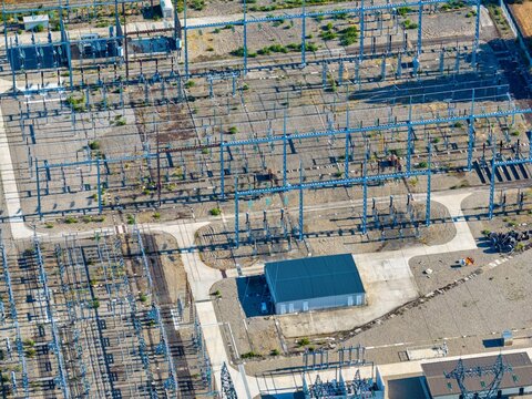 Aerial view of the electrical substation with metal structures, power lines, and transformers set on a gravel ground in Hombourg, Grand Est, France.