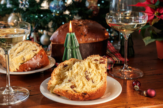 Festive Christmas Table With Sliced Panettone, Wine Glasses and Candle Beside Tree