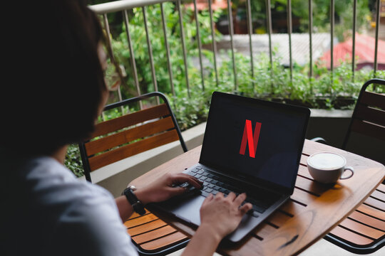 Bangkok, Thailand. August 16, 2026; Woman using laptop displaying Netflix homepage application while sitting outdoors in cozy environment.