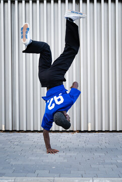 Male breakdancer performing handstand freeze on urban street showcasing agility and hip hop culture