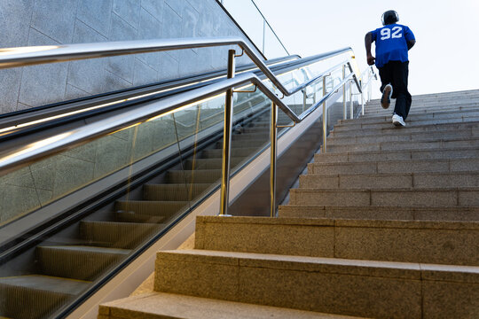 Black man running up urban stairs for fitness workout, demonstrating determination and achieving health goals