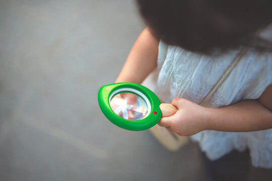 Child using magnifying glass to examine flower, curiosity, nature exploration and early childhood learning