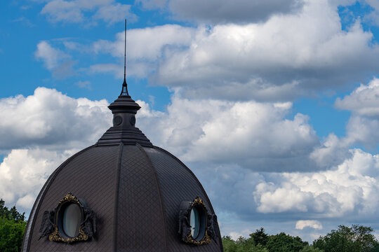 Baroque style domed rooftop with spire against blue sky, European architecture landmark, close-up exterior shot