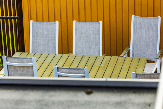 Close-up view of outdoor dining table with chairs beside wooden house wall. Sweden.