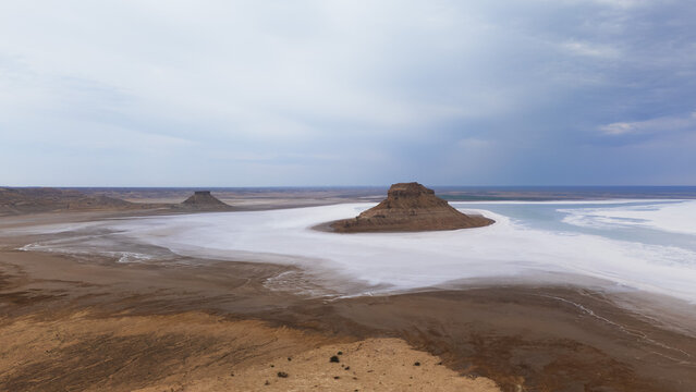 Panoramic view of Karynzharyk Depression in Mangystau Region, Kazakhstan. Majestic limestone rock formations standing out of a white salt pan (Sor) filled with milky water under a dramatic overcast sk