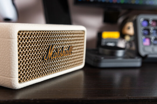 Macro close up of Marshall Emberton III cream wireless bluetooth speaker with brass logo on dark desk