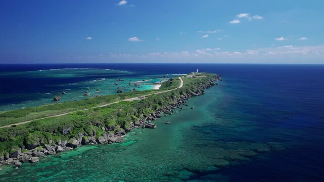 東平安名崎の全景と遠くに見える灯台｜宮古島・沖縄の環礁とエメラルドグリーンの海の空撮パノラマ/Panoramic aerial view of Higashi-Hennazaki Cape with distant lighthouse, fringing reef and emerald green ocean, Miyako Island, Okinawa, Japan