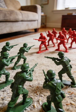 Close‑up scene of green and red toy soldiers arranged on a carpeted floor, facing each other in a playful indoor battle setup with detailed miniature combat poses