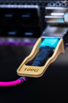 Close up of a 100Gbit network transceiver with a patch cable inserted into a switch, high speed broadband networking, data transmission, telecommunications infrastructure, and modern internet connecti